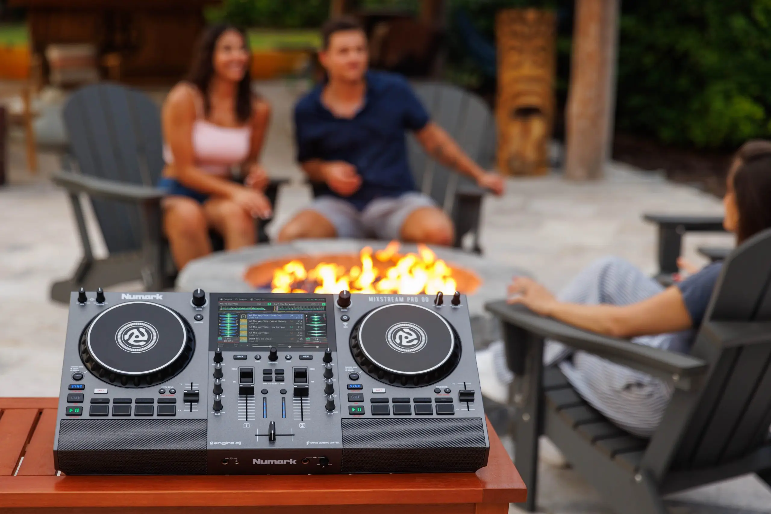 Bàn DJ Numark Mixstream Pro Go màu bạc đang được sử dụng trong một buổi biểu diễn ngoài trời
